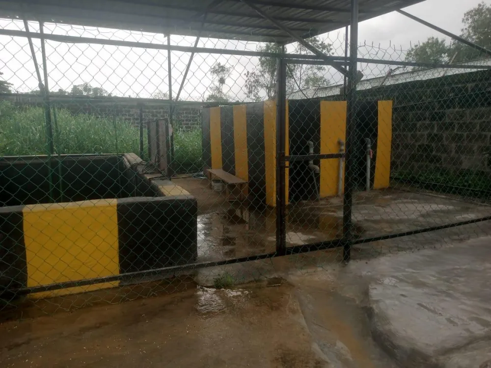 Revamped sewage treatment plant with yellow and black safety-striped walls behind a chain-link fence